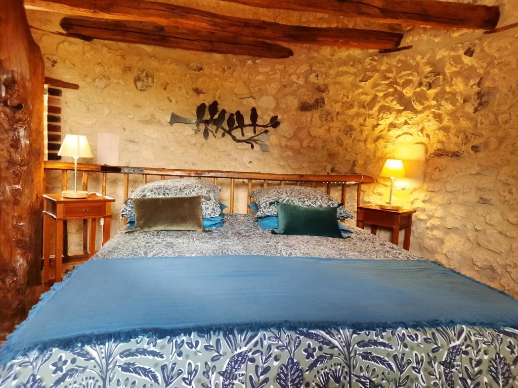 a bedroom with a large bed in a stone wall at La Tour de rêves in Beaumont-la-Ronce