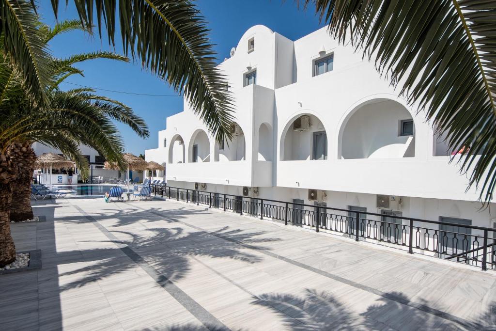 a white building with palm trees in front of it at Villa Valvis in Perissa