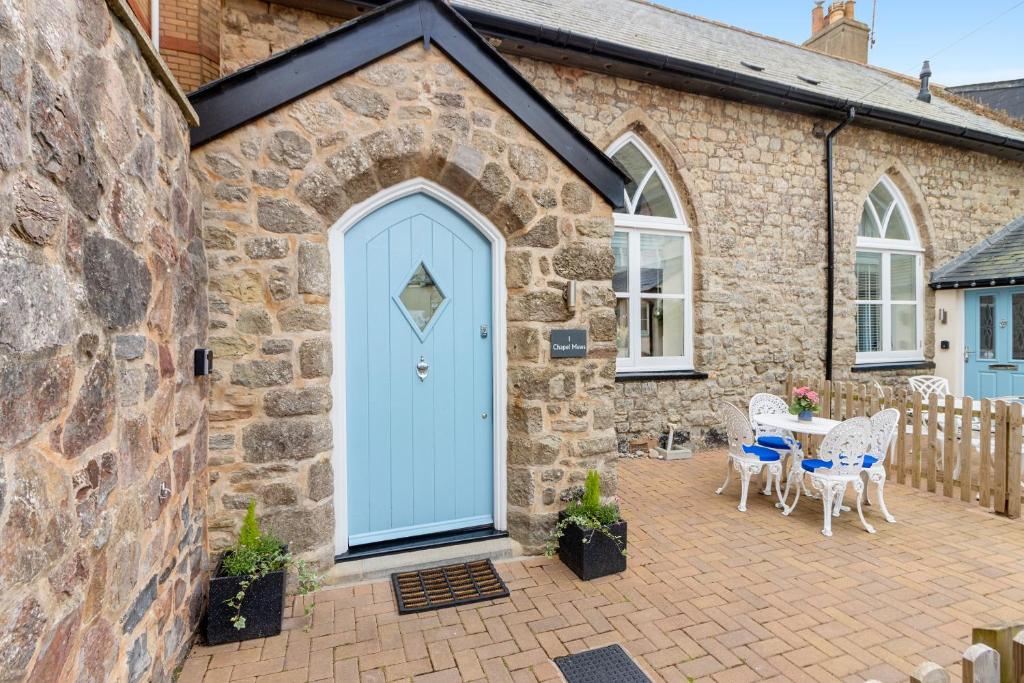 kamienny dom z niebieskimi drzwiami i patio w obiekcie 1 Chapel Mews w mieście Sidmouth