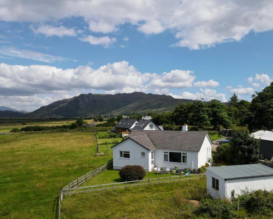 a white house in a field with mountains in the background at The Sheiling holiday home with gorgeous views over the isles in Arisaig