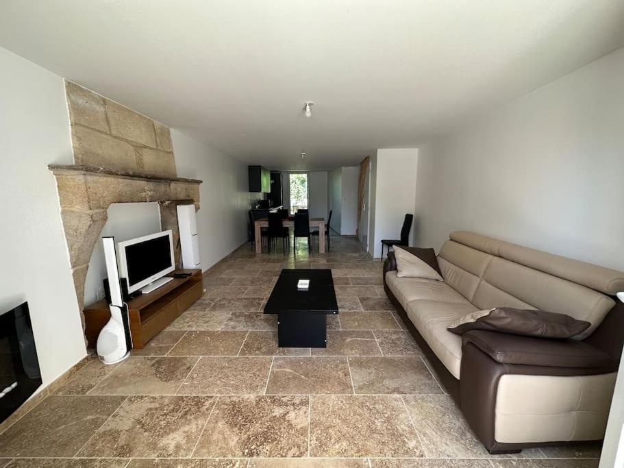 un salon avec un canapé et une télévision dans l'établissement Maison au calme, à Sauveterre-de-Guyenne