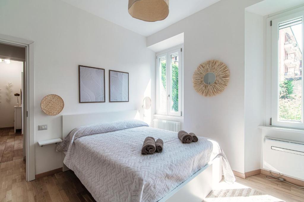 ein weißes Schlafzimmer mit einem Bett mit zwei Schuhen darauf in der Unterkunft Casa Giulini - The House Of Travelers in Como