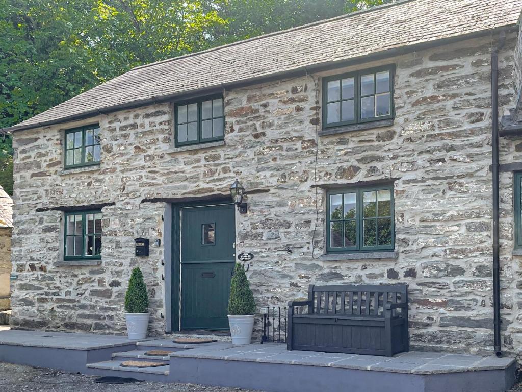 a stone house with a green door and a bench at Old Stables Cottage in Blaenporth