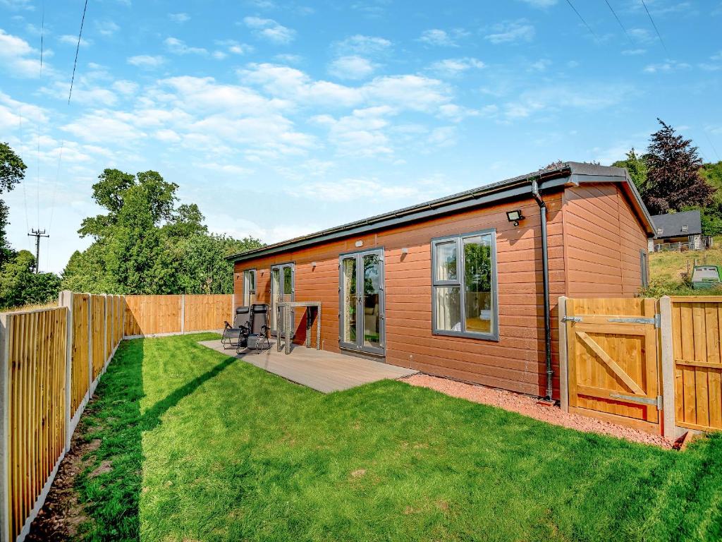 a small house with a wooden fence and a yard at West End Farm Lodge Alabaster in Lydbrook