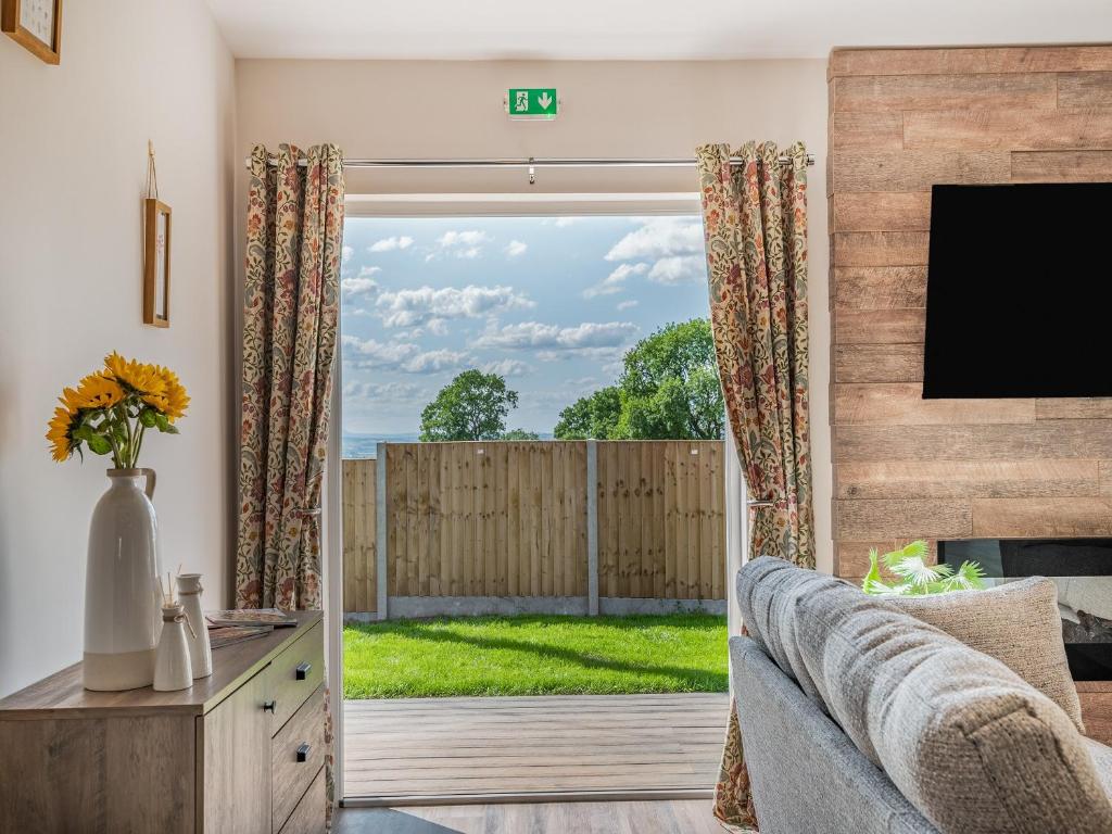 un soggiorno con divano e porta scorrevole in vetro di West End Farm Lodge Alabaster a Lydbrook