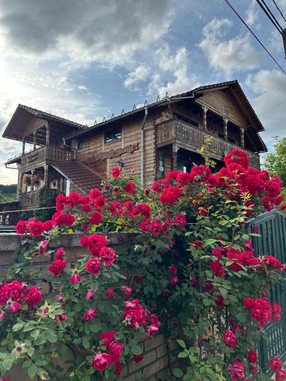 ein Haus mit roten Rosen davor in der Unterkunft La Curtea Veche in Lăpuş