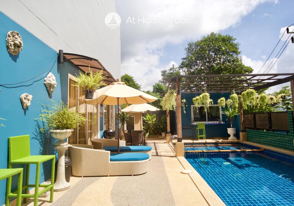 a house with a swimming pool with chairs and an umbrella at Ao Nang Mountain View Pool Villa in Ao Nang Beach