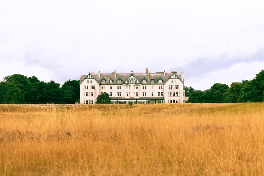 a large white house on a hill in a field at Dornoch Station in Dornoch