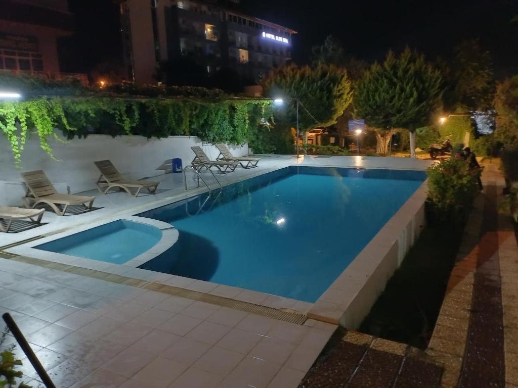 a swimming pool at night with chairs around it at Near the Ladies beach-100m only in Aydın