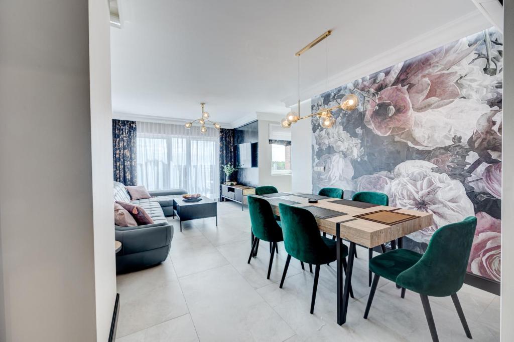 a dining room with a table and green chairs at APARTAMENTY Z TARASEM NA DACHU NA WYDMACH W MIĘDZYWODZIU in Międzywodzie