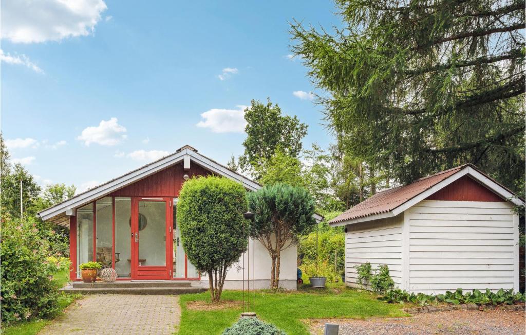 uma pequena casa com uma garagem vermelha e branca em Cozy Home In Frvang With Outdoor Swimming Pool em Fårvang
