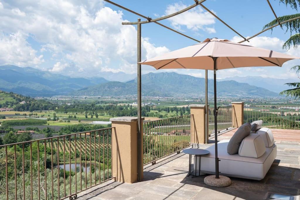 a patio with an umbrella and a chair and a table at Peaceful Luxury Farmhouse - Stunning Alps Views in Saluzzo