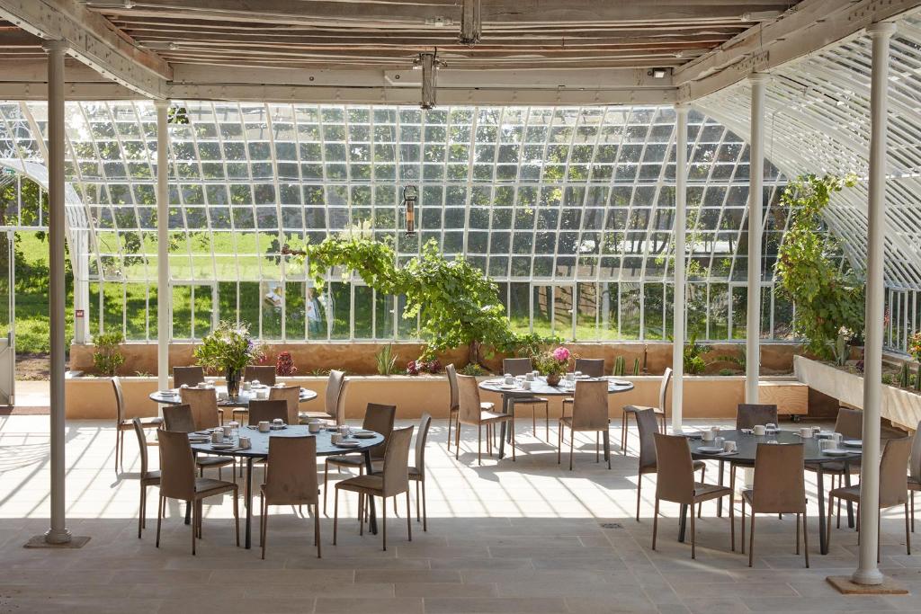 a restaurant with tables and chairs in a greenhouse at DOMAINE LE MEZO in Ploeren