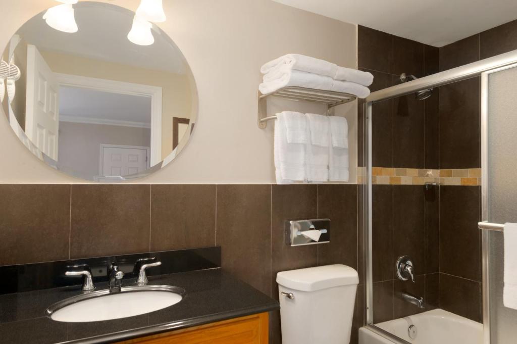 a bathroom with a sink and a mirror and a toilet at Ramada by Wyndham Miami Springs/Miami International Airport in Miami