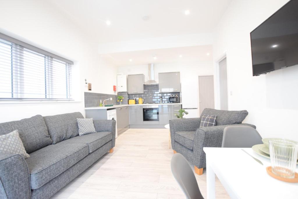 a living room with two couches and a kitchen at Stylish City Centre Apartments in Lincolnshire