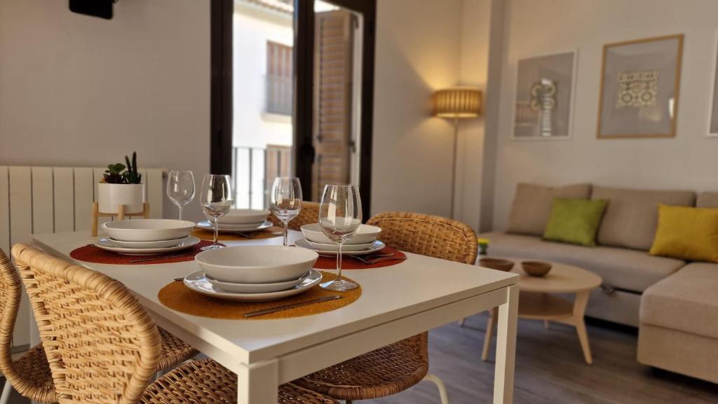 una mesa de comedor con platos y copas de vino en IMEDA Apartamentos Piedra Santa, en Granada