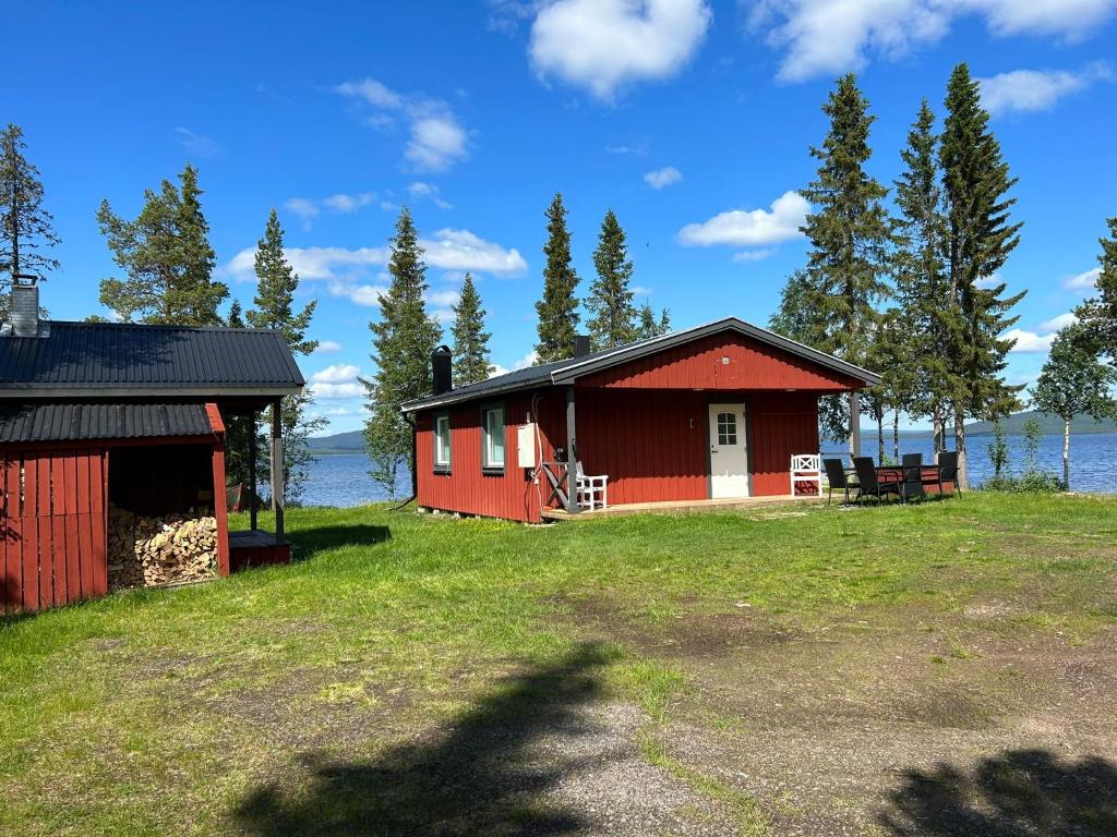 a red building on a field next to the water at Camp Caroli 2.0 in Jukkasjärvi