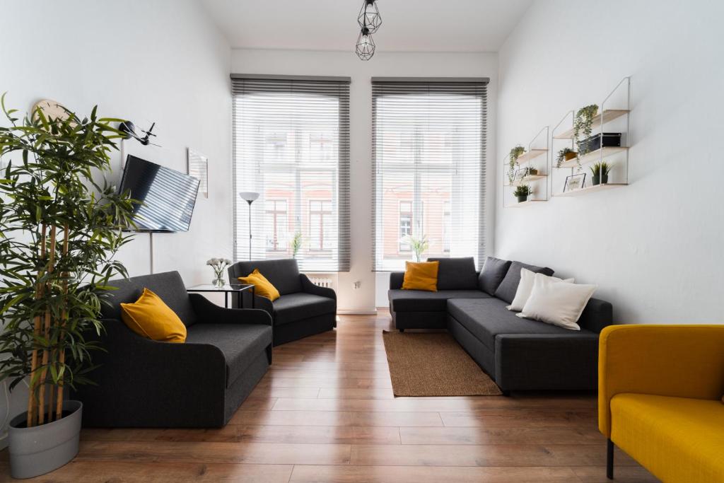 ein Wohnzimmer mit schwarzen Sofas und gelben Kissen in der Unterkunft Oławska - City Centre - 3 Rooms - 200m to Market Square in Breslau