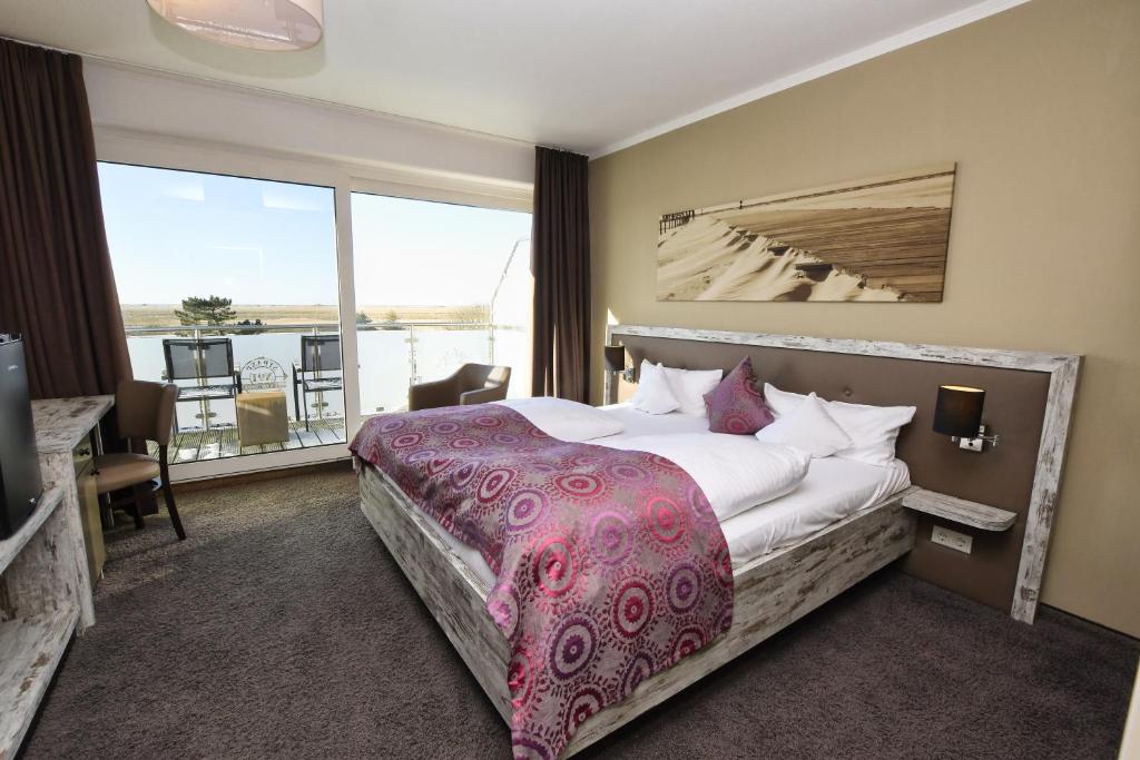 ein Hotelzimmer mit einem großen Bett und einem Balkon in der Unterkunft Hotel Strand No.1 in Sankt Peter-Ording