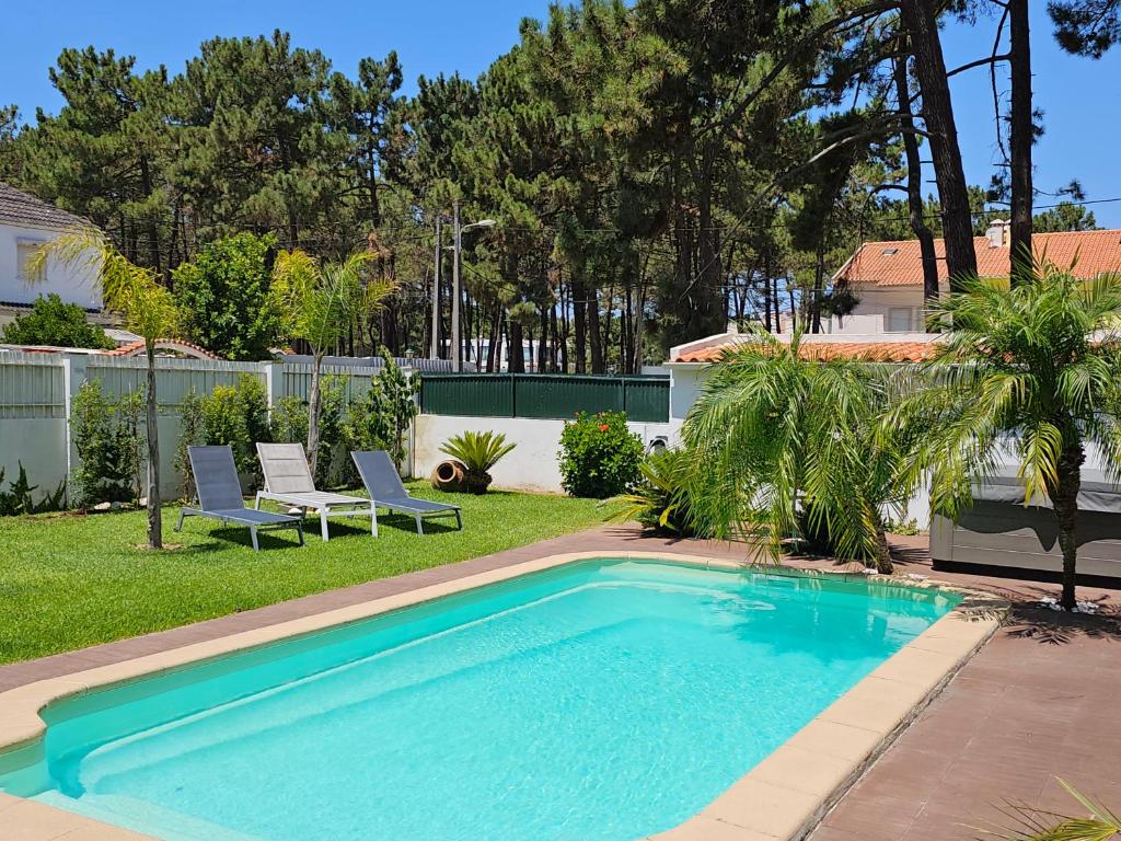 a swimming pool in a yard with two lawn chairs at Guest House Ruceel Aroeira in Almada