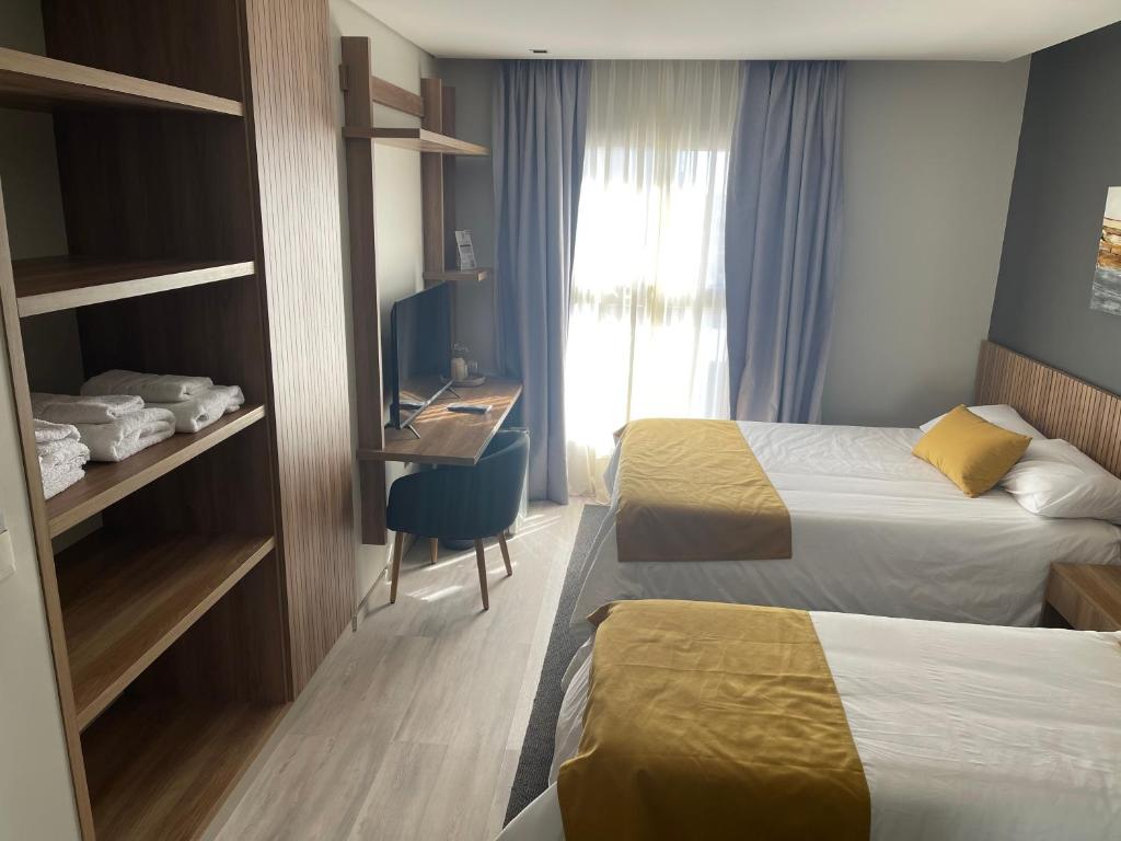 a hotel room with two beds and a desk at Urban Suites Oliva in Oliva