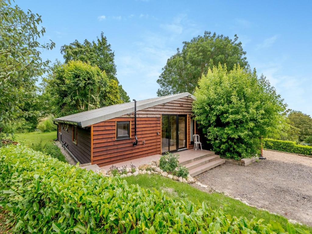 eine kleine Holzhütte mit einer Veranda im Garten in der Unterkunft Eeyores House - Uk43487 in Aldington