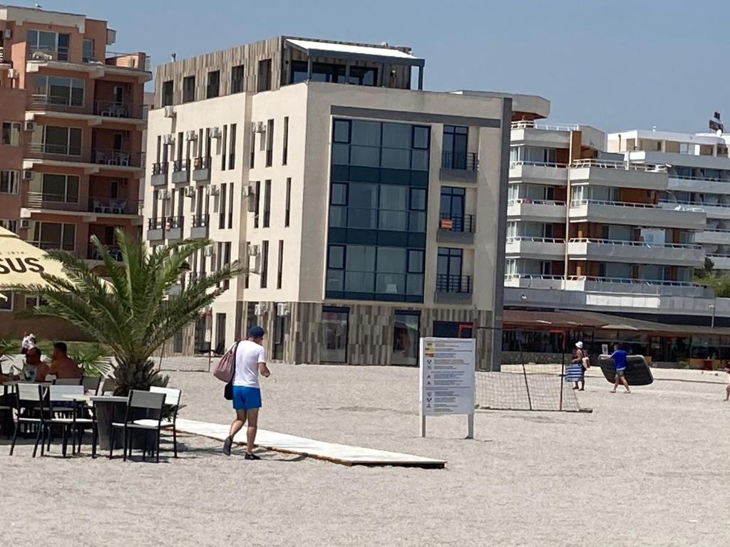 a man standing on the beach in front of a building at Beach Rooms Roberta in Mamaia