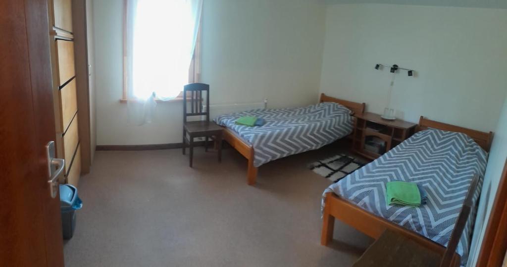 Zimmer mit 2 Betten, einem Tisch und einem Stuhl in der Unterkunft Jaunvaltes in Ragana