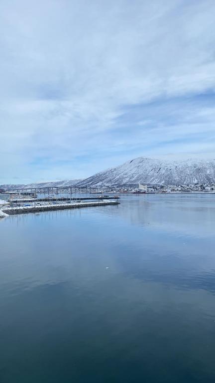 a large body of water with snow covered mountains at Seaside panorama in Tromsø
