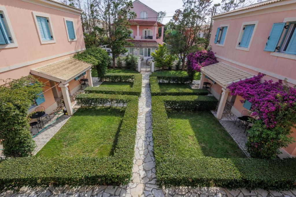 Satori Boutique Hotel في أكارافي: حديقة بين مبنيين بها زهور أرجوانية