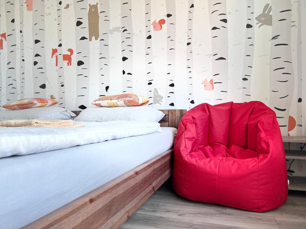 a bedroom with a bed and a red chair at Apartmány Catalina in Nesvady