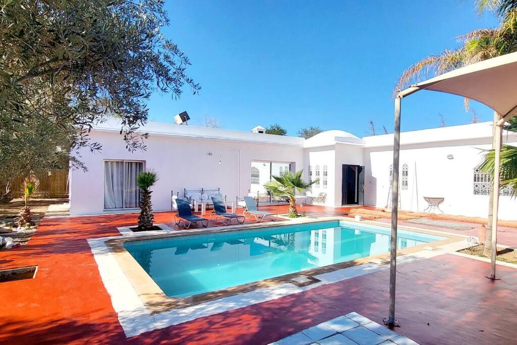 - une piscine en face d'une maison blanche dans l'établissement Villa Dar Sukar, à Marrakech