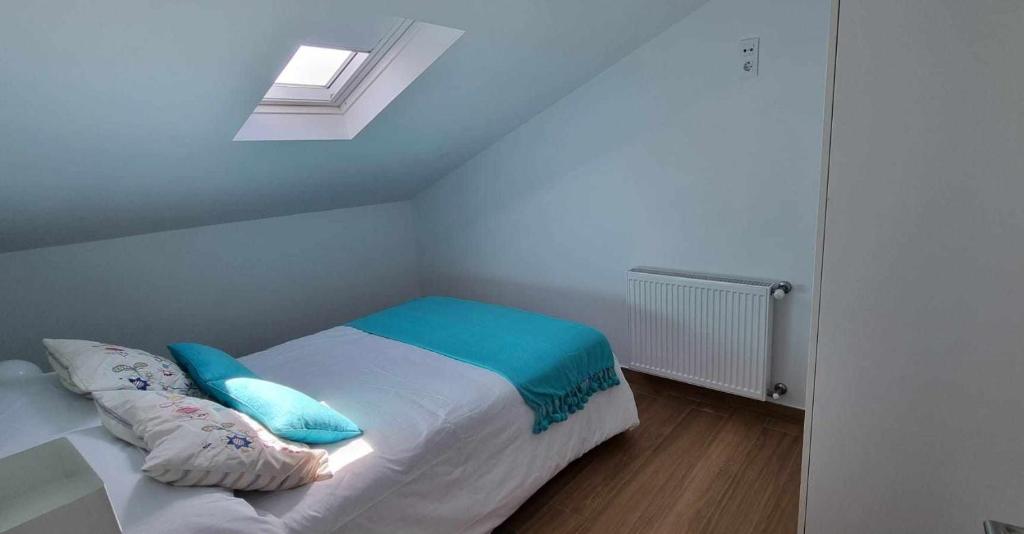Un dormitorio con una cama con almohadas azules y una ventana en Mar de Queiruga 22 Tarrío, en Porto do Son