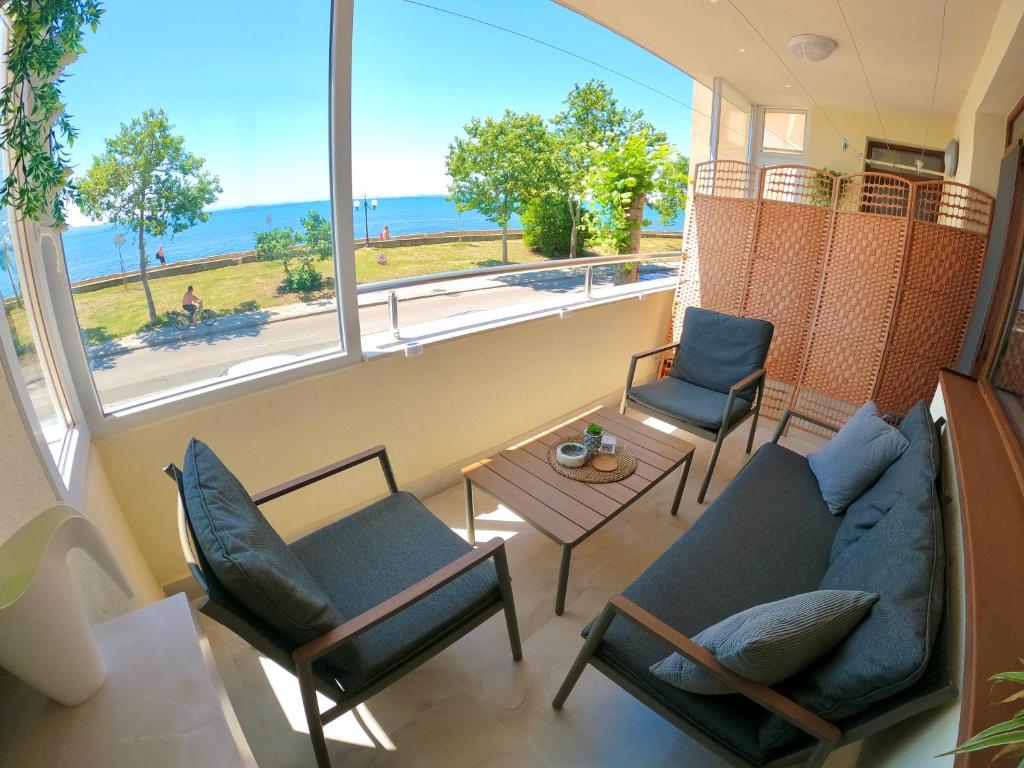 Sala de estar con sofá y sillas y vistas al océano en Sunset Yavorov Pomorie en Pomorie