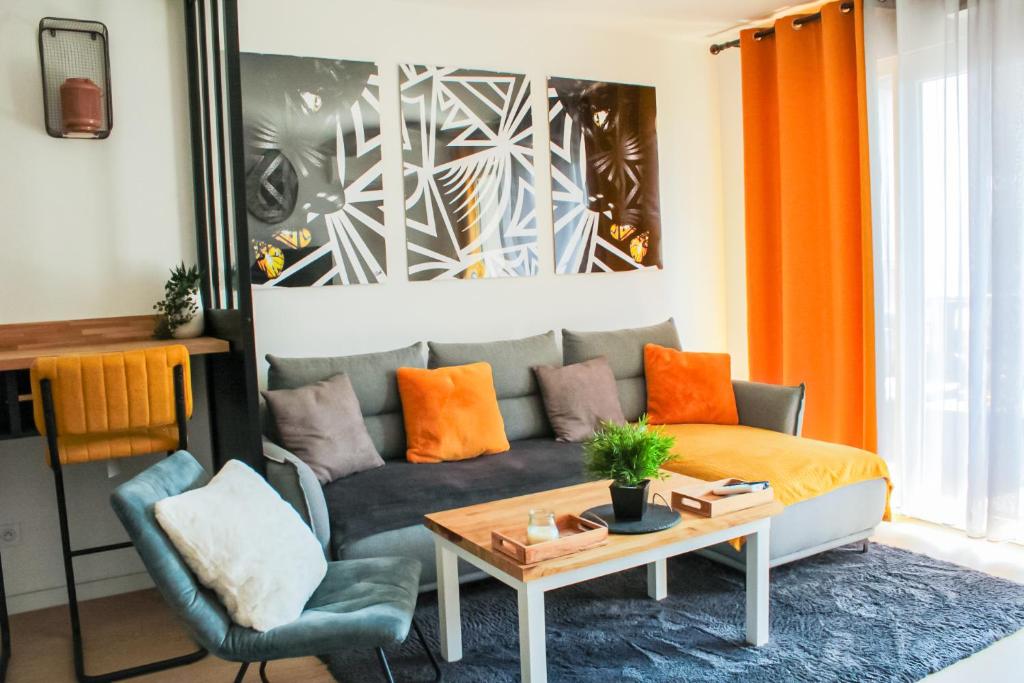 a living room with a couch and a table at Appartement nouveaux quartier Bologne à deux pas de Mosson, WiFi, climatisation et parking gratuit in Montpellier