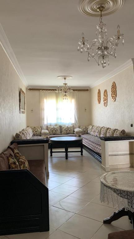 ein Wohnzimmer mit einem Sofa und einem Kronleuchter in der Unterkunft APPARTEMENT in MARTIL Complexe Résidentiel Al Karama 1 in Martil