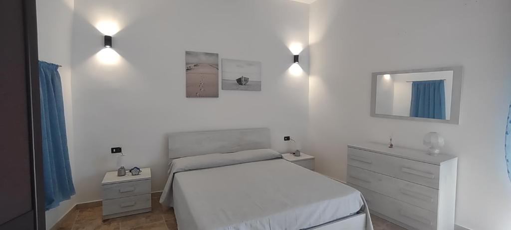 una camera bianca con letto e cassettiera di Casa Alisea a Castellaneta