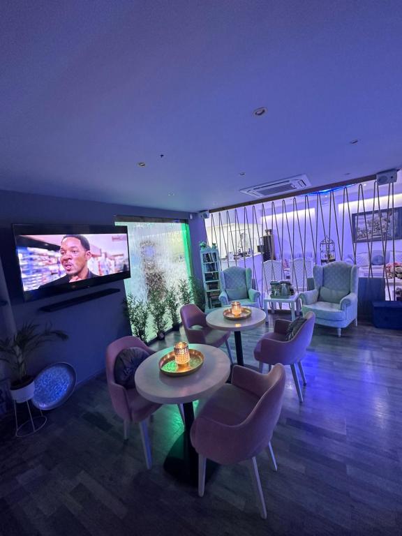 a living room with tables and chairs and a flat screen tv at Thalia deco City & Beach Hotel in Hersonissos