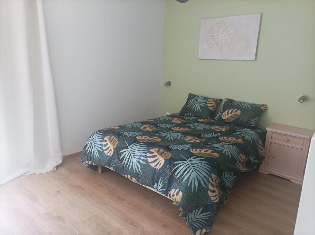 1 dormitorio con 1 cama con manta y hojas de palmera en Gite paisible, en Seyssel