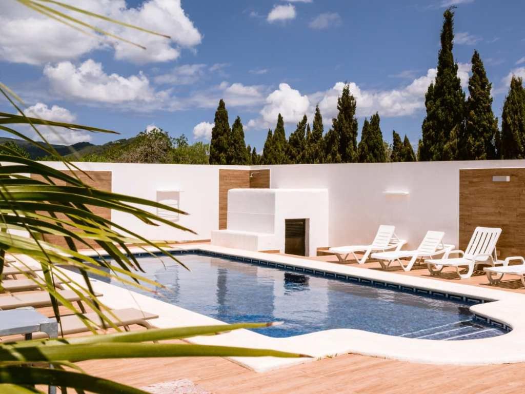 a swimming pool with chairs and a house at Can Pep Luis Can Pep Mortera is located in the beautiful countryside near to Playa den Bossa in Ibiza Town