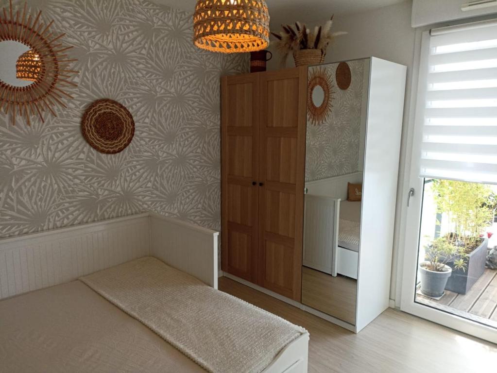 a room with a bed and a cabinet and a window at Chambre nature chez l'habitant in Strasbourg