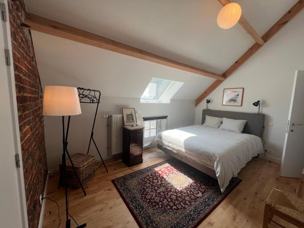 a bedroom with a bed and a lamp and a rug at Le Gîte du Jardinier in Tournai
