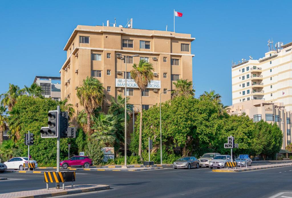 فندق المنصوري مانشنز في المنامة: مبنى فيه سيارات تقف في شارع المدينة