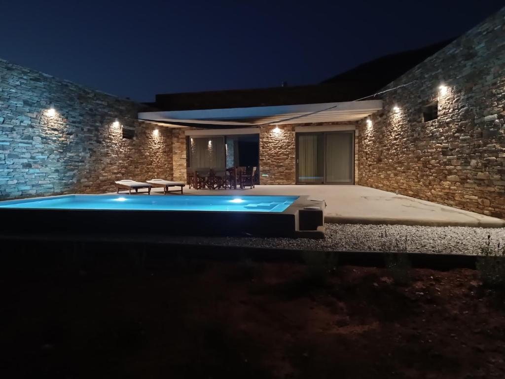 una piscina frente a un edificio por la noche en Gray and Blue, en Ándros