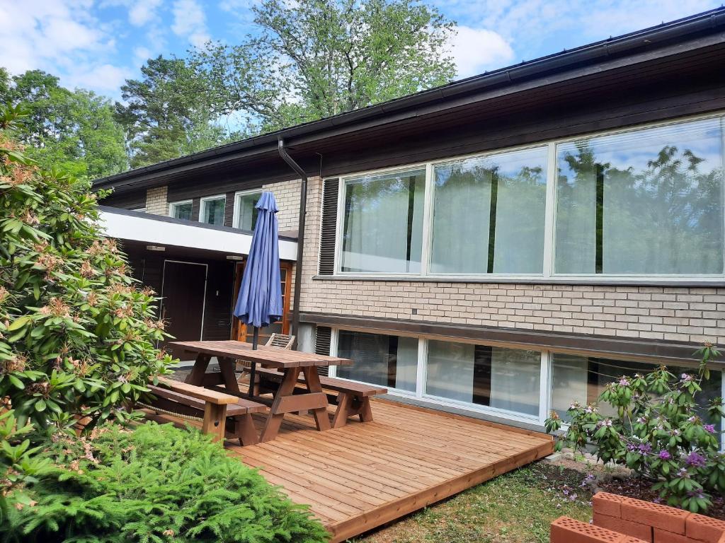 una terraza de madera con mesa de picnic y sombrilla en Family House Kupittaa Diplomat, Sauna, Garden, whole house for you, en Turku