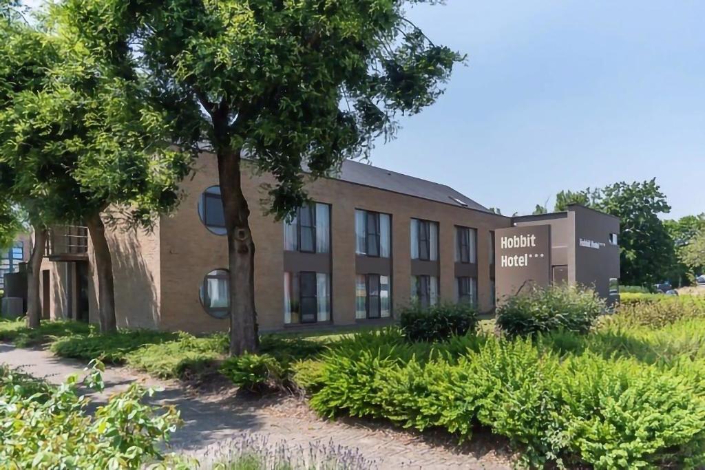 un immeuble de bureaux avec un arbre devant lui dans l'établissement Hobbit Hotel Mechelen, à Malines