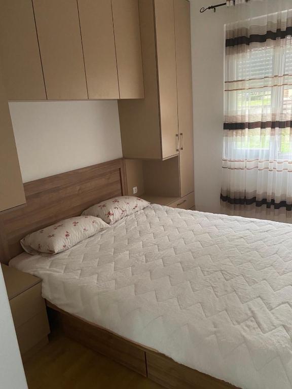 una camera da letto con un grande letto bianco con una finestra di BS Apartman a Podgorica