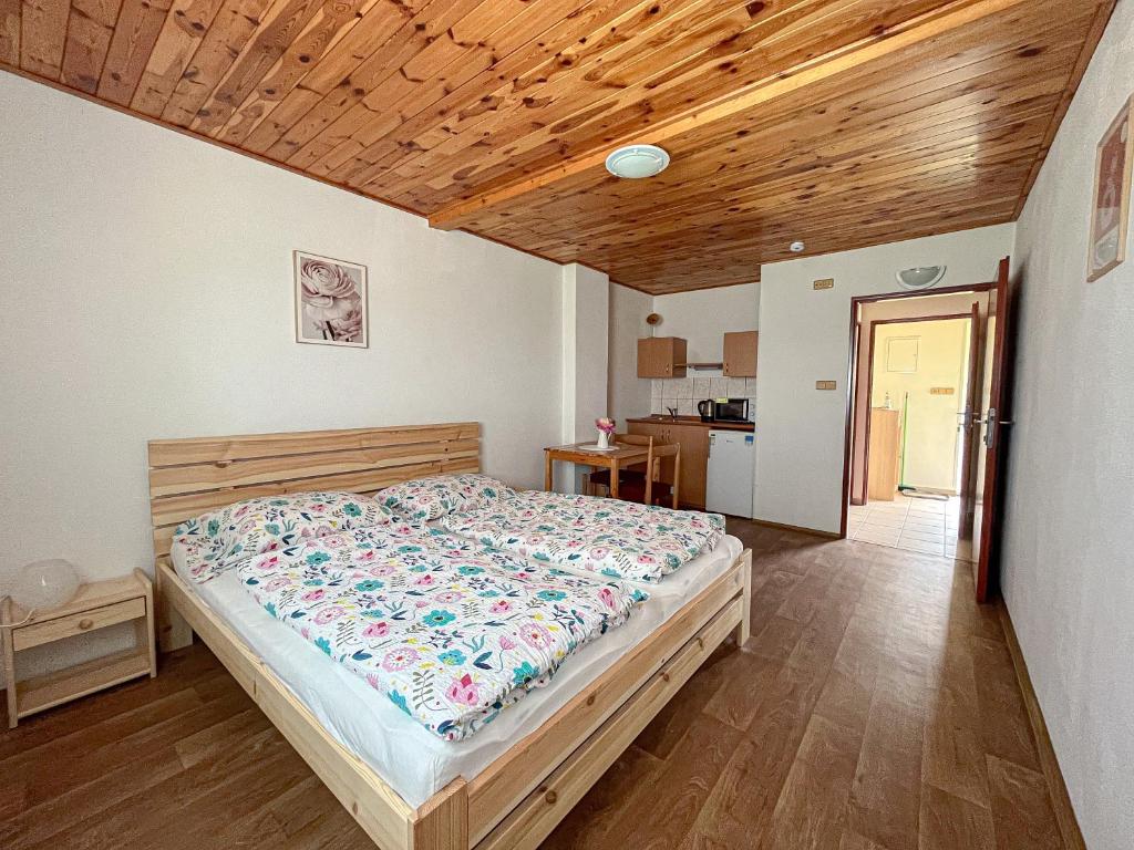 a bedroom with a bed and a wooden ceiling at Penzion Hevera in Kuchařovice