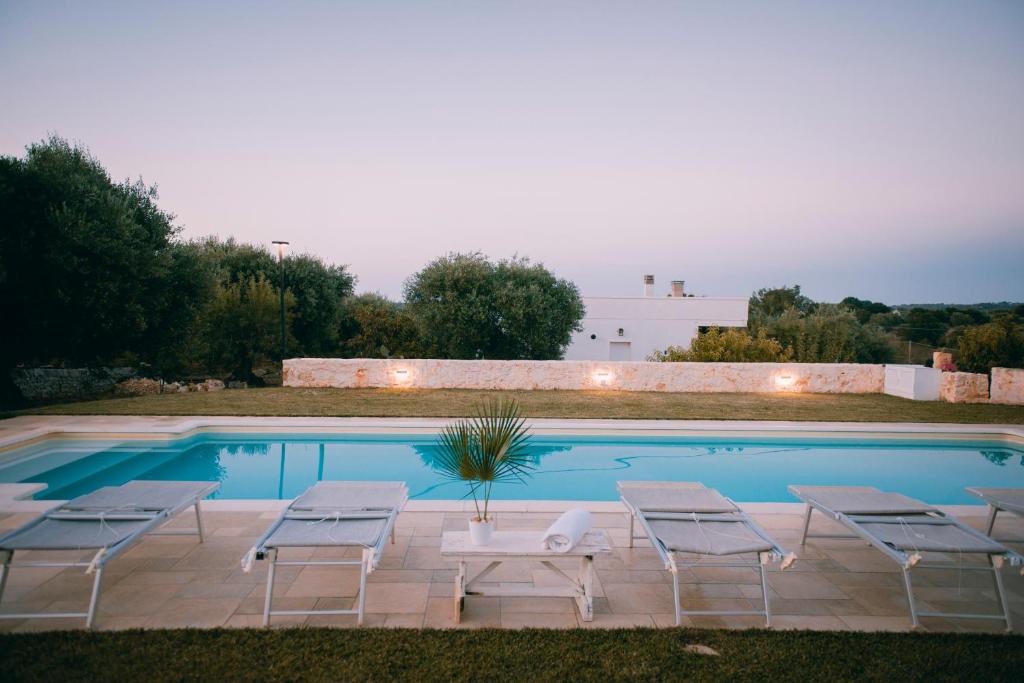 a swimming pool with chairs and a table and a pool at Villa Comes in Monopoli