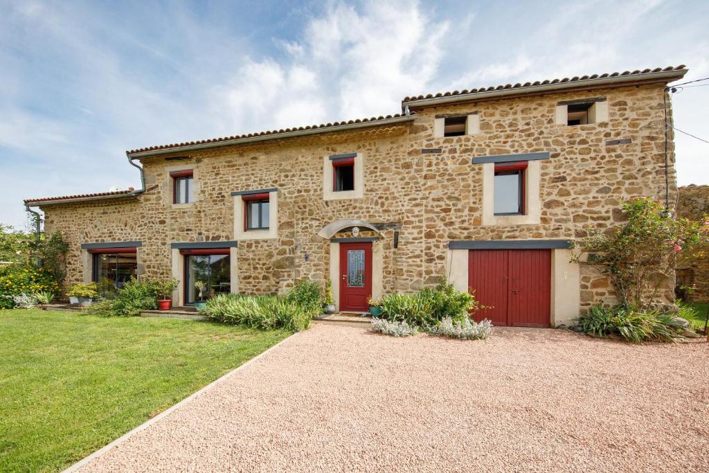 a stone house with red doors and a yard at LE CLOS DU MOUY in La Souche